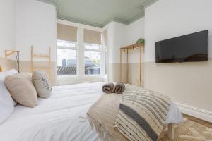 a bedroom with a large white bed with a flat screen tv at Stoneholme Short Stay - Clare Street Apartments in Blackpool