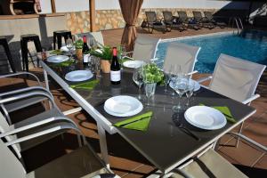 a table with plates and wine glasses next to a pool at Villa Lluna Sitges 15 minutes drive from Sitges Swimming pool XXL 16 people in Olivella