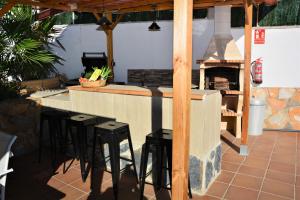 a kitchen with a bar with stools and a fireplace at Villa Lluna Sitges 15 minutes drive from Sitges Swimming pool XXL 16 people in Olivella