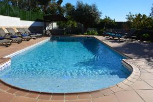 ein großer Pool mit Stühlen und einem Sonnenschirm in der Unterkunft Villa Lluna Sitges 15 minutes drive from Sitges Swimming pool XXL 16 people in Olivella