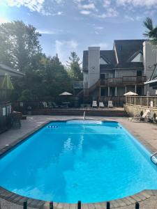 a large blue swimming pool in front of a house at Slope-side Studio Bliss Ski-inSki-out, Renovated At Blue, Hot Tub, Fast Wi-Fi in Blue Mountains