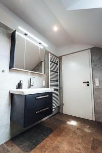 a bathroom with a sink and a mirror and a door at Ferienwohnungen Am Heidegarten in Schneverdingen +25 photos