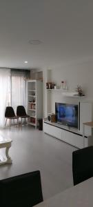ein Wohnzimmer mit einem großen TV und ein Wohnzimmer mit Stühlen in der Unterkunft Apartamento Cuidad Ciencias in Valencia