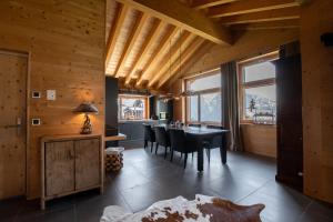a dining room with a table and chairs and windows at ANNA ISABELLE PENTHOUSE in Riederalp