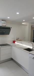 cocina blanca con armarios blancos y luz roja en Apartamento Cuidad Ciencias, en Valencia