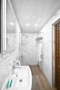 a white bathroom with a sink and a shower at Aurelia Hotel & Restaurant in Dilijan
