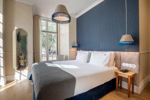 a bedroom with a large bed with a blue wall at Boemio FLH Hotels in Lisbon