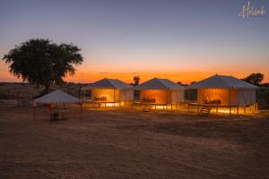 grupa namiotów na pustyni o zachodzie słońca w obiekcie Helsinki Desert Camp w mieście Jaisalmer