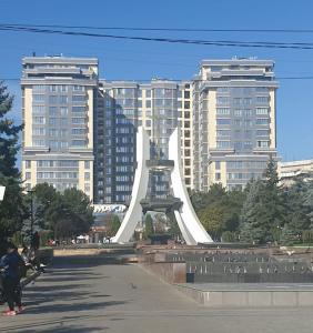 a large white sculpture in front of tall buildings at Modern 1BD apartment with living room in the park zone in Chişinău