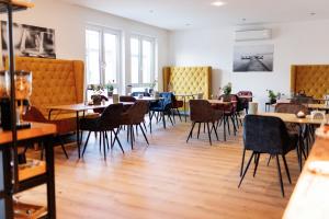 een eetkamer met tafels, stoelen en ramen bij Kracher Hotel Doppelzimmer in Illmitz