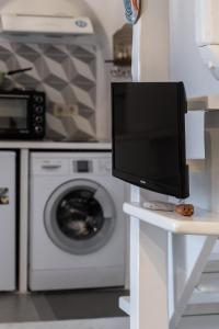 - une télévision sur une table blanche dans une cuisine avec un lave-linge dans l'établissement Little house town mykonos, à Mykonos