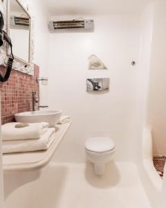 a white bathroom with a toilet and a sink at Little house town mykonos in Mikonos