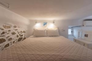 a bedroom with a large bed with white sheets at Little house town mykonos in Mikonos