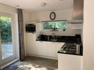 a kitchen with white cabinets and a clock on a window at Karekiet 42 in Oudemirdum