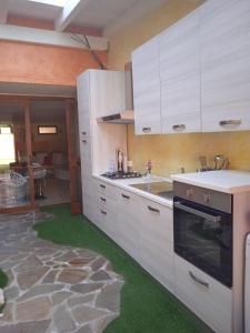a kitchen with white cabinets and a green floor at Appartamento Villa Serena due in Maracalagonis