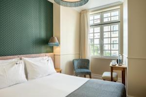 um quarto com uma cama, uma cadeira e uma janela em Boemio FLH Hotels em Lisboa