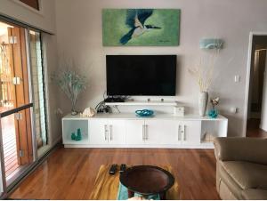 - un salon avec une télévision sur un centre de divertissement blanc dans l'établissement Island Breeze Fiji, à Savusavu