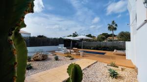 un patio trasero con piscina y una casa en Lago Resort Menorca - Villas & Bungalows del Lago en Cala'n Bosch