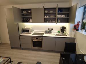 a small kitchen with a sink and a microwave at Luxurious Short Stay Flat in Milton Keynes in Milton Keynes