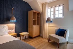 a bedroom with a bed and a chair and a window at Boemio FLH Hotels in Lisbon