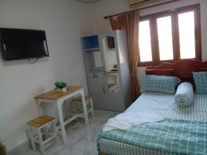 a bedroom with a bed and a table and a television at Ban Saylomleng Residence in Vientiane