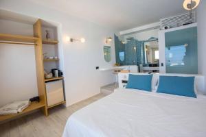 ein Schlafzimmer mit einem großen weißen Bett mit blauen Kissen in der Unterkunft Caldera's Majesty in Imerovigli
