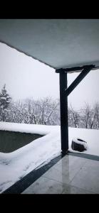 un porche cubierto de nieve con un campo cubierto de nieve y árboles en Villa a vamos, 