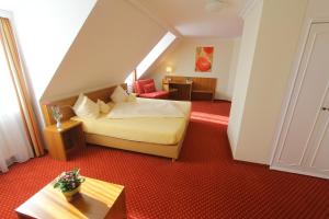 Habitación de hotel con cama, silla y mesa en Abasto Hotel Eichenau, en Eichenau