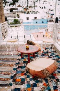 un balcón con mesa y sillas y un gato durmiendo en una alfombra en The Riad Hostel Tangier en Tánger