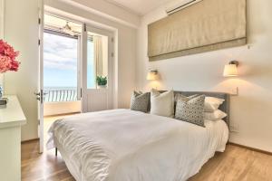 una camera da letto con un grande letto bianco e una finestra di Charming Clifton Apartment - Number 4701 a Città del Capo