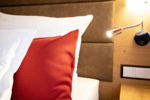 a bedroom with a bed with a red pillow and a lamp at Park Hotel Laim in Munich