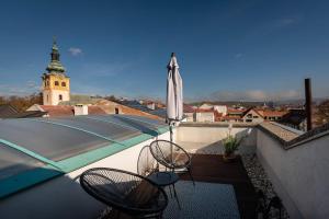 - un balcon avec 2 chaises et un parasol dans l'établissement Apartmán pod Vežou 2, à Banská Bystrica