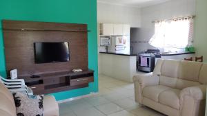 sala de estar con sofá y TV y cocina en Casa Pestana - Ilha Comprida en Ilha Comprida