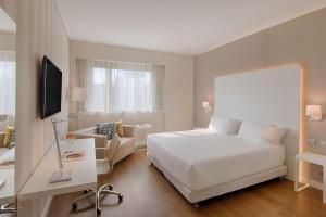 um quarto de hotel com uma cama branca e um sofá em NH Torino Centro em Turim