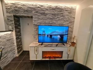 a flat screen tv on a tv stand with a fireplace at Roggendorf Zimmervermietung in Roggendorf