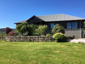 a house with a stone wall and a yard at Drumhead Cottage Finzean, Banchory Aberdeenshire Self Catering with Hot Tub in Finzean