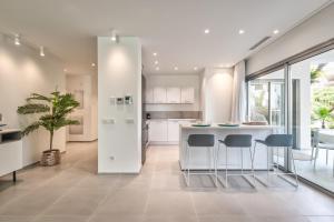 a kitchen with white cabinets and a island with bar stools at Jardines - Adama 01 VISTA PISCINA & JARDIN 2B in Palm-mar