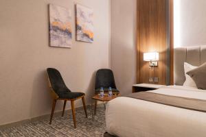 um quarto de hotel com uma cama e duas cadeiras em فندق ركاز الماسي - Rekaz Diamond Hotel em Sīdī Ḩamzah