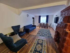 a living room with blue couches and a dining room at Casa de la Chiojdu in Bîsca Chiojdului