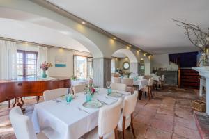 a restaurant with white tables and chairs and a piano at La Tartana Hotel Boutique in La Herradura