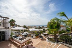 an outdoor patio with tables and umbrellas on a building at La Tartana Hotel Boutique in La Herradura