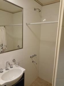 y baño blanco con lavabo y ducha. en Edificio NEA en Corrientes