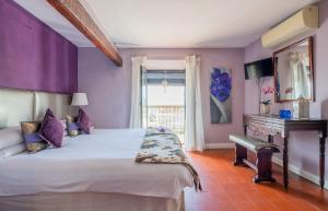 a bedroom with a bed with purple walls and a desk at La Tartana Hotel Boutique in La Herradura