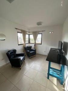 un soggiorno con sedie in pelle nera e TV di Luis II a Villa María 1 altra foto