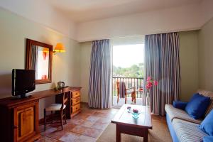 a living room with a couch and a television at Hotel Cala Sant Vicenç - Adults Only in Cala de Sant Vicenc