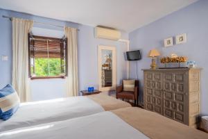 a bedroom with two beds and a dresser and a window at La Tartana Hotel Boutique in La Herradura