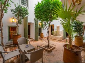 um pátio com plantas e uma mesa e cadeiras em Riad Timila em Marraquexe