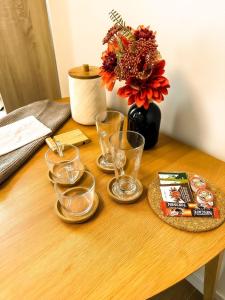 a wooden table with glasses and a vase with flowers at Riga Center - Quiet Studio - 5 min to Old Town & NFLX in Rīga