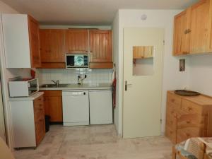 uma cozinha com armários de madeira e um frigorífico branco em Appartement Le Pleynet, 2 pièces, 5 personnes - FR-1-557A-45 em La Ferrière