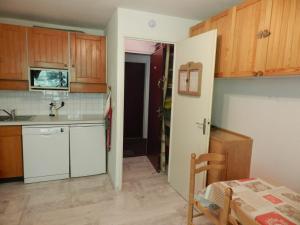 uma cozinha com armários de madeira e um frigorífico branco em Appartement Le Pleynet, 2 pièces, 5 personnes - FR-1-557A-45 em La Ferrière